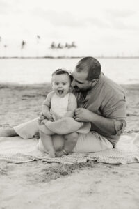 baby and dad at the beach sitting on the sand