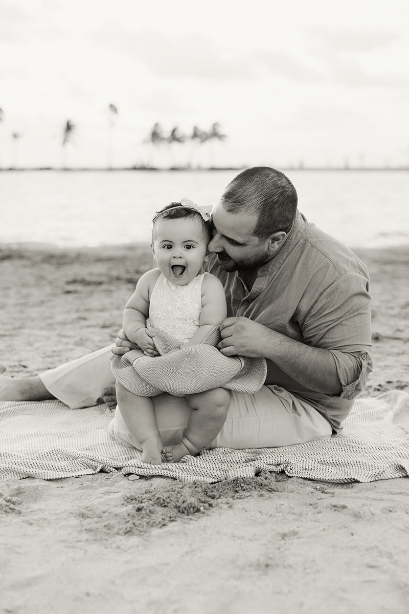 baby and dad at the beach sitting on the sand