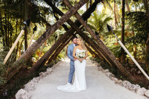 bride, white dress, groom, blue suit, sunrise, beach, under canopy of palm trees
