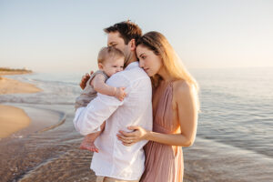 family of three at the beach during sunrise, mom pink dress