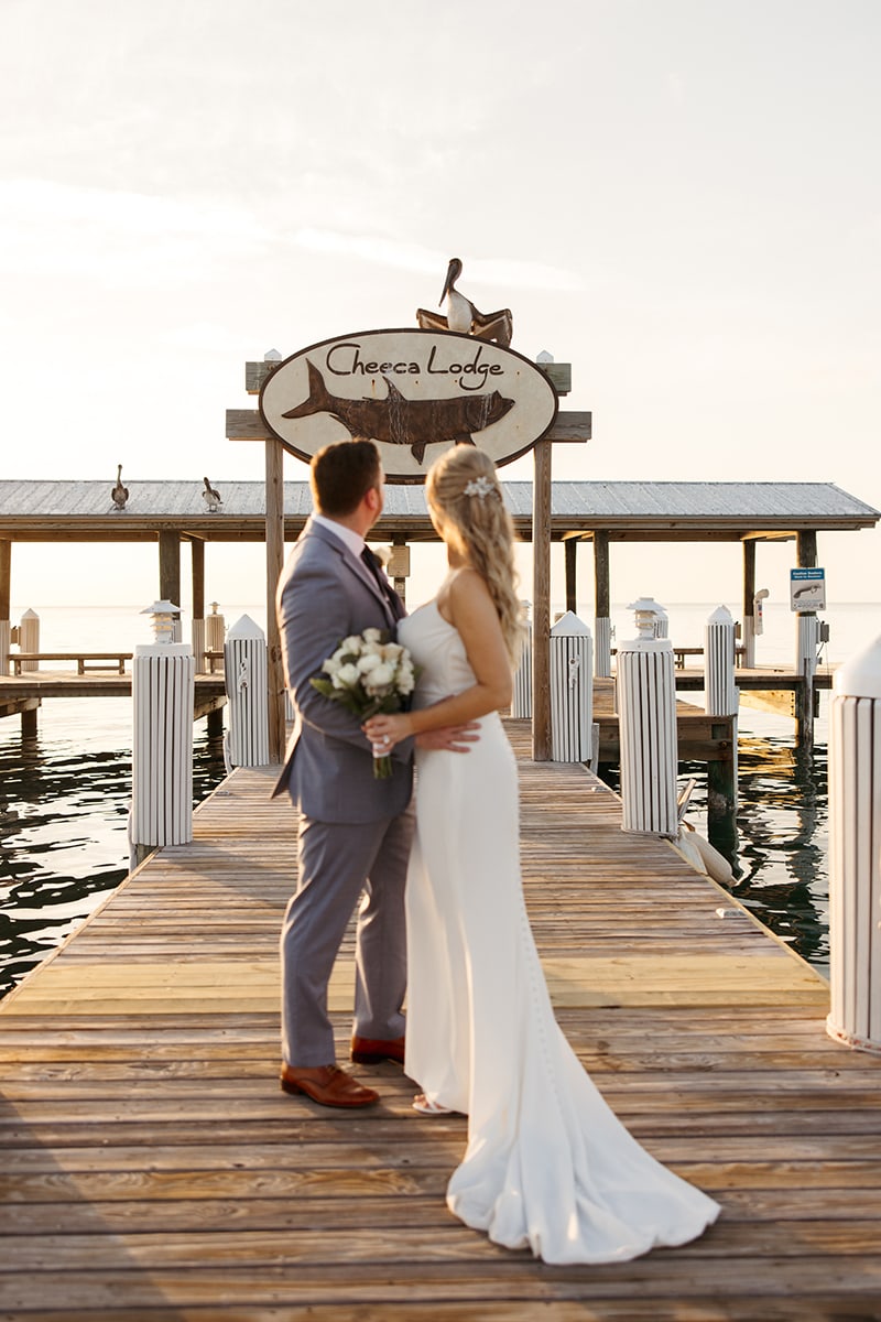 bride, white dress, groom, blue suit, sunrise, pier, looking at seagull