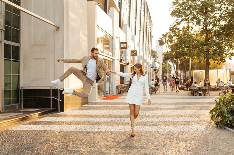 Wedding Photography and Elopement Photography, couple walking down the street with groom jumping into the air